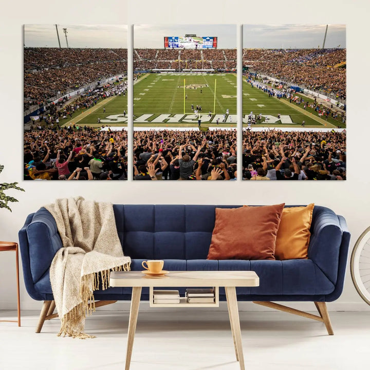 The living room features premium artwork, the "UCF Knights Football Team Print - Orlando FBC Mortgage Stadium Wall Art Canvas Print," a three-panel canvas piece depicting a bustling football stadium. Handmade in the USA, this artwork adds a dynamic and vibrant touch to your space.