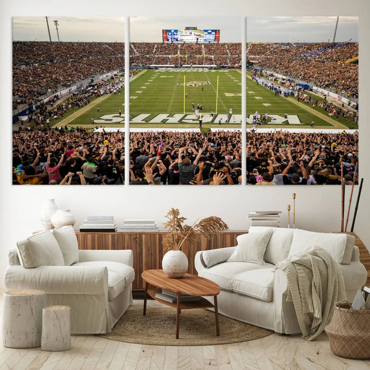 The living room features premium artwork, the "UCF Knights Football Team Print - Orlando FBC Mortgage Stadium Wall Art Canvas Print," a three-panel canvas piece depicting a bustling football stadium. Handmade in the USA, this artwork adds a dynamic and vibrant touch to your space.