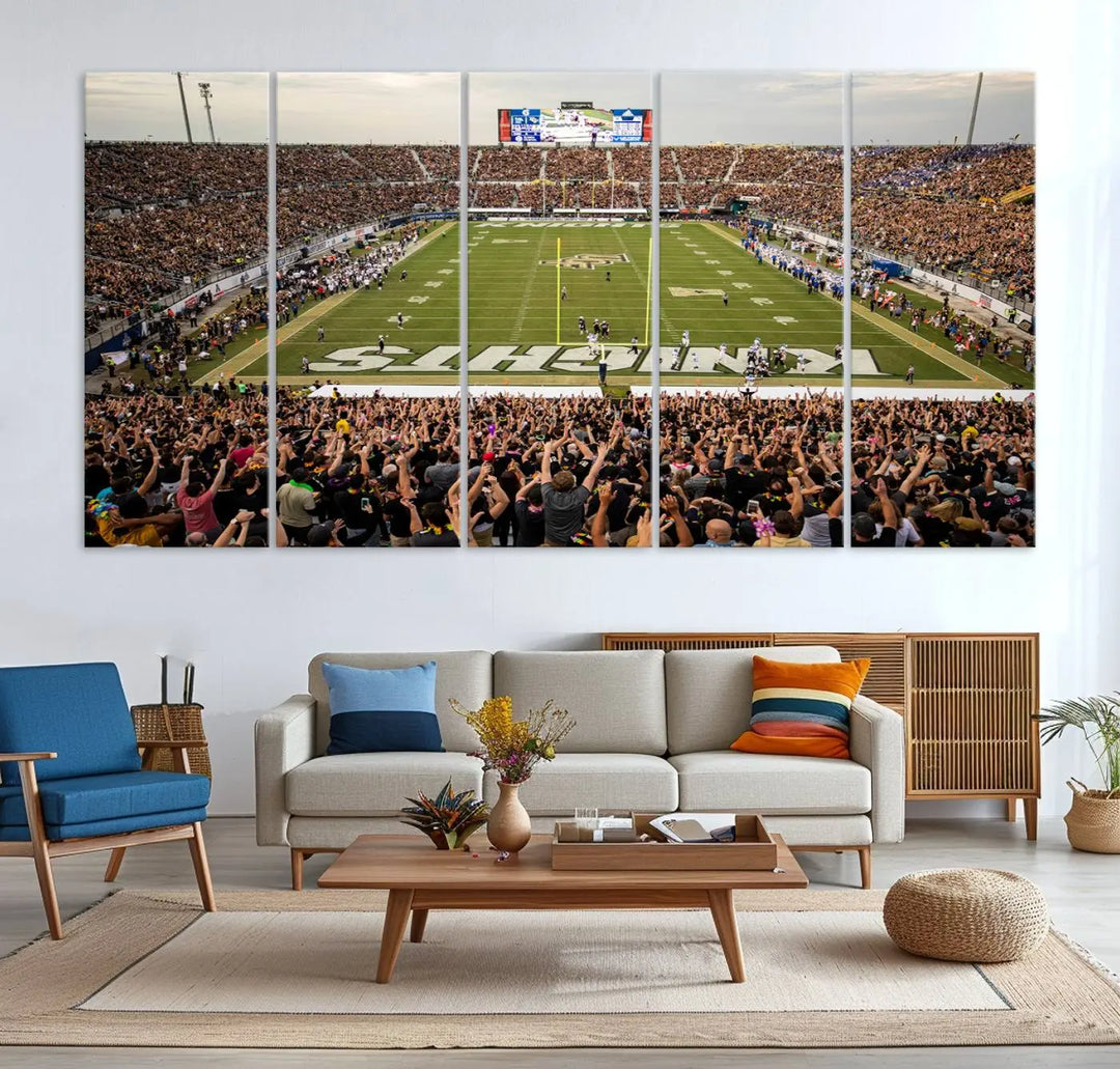 The living room features premium artwork, the "UCF Knights Football Team Print - Orlando FBC Mortgage Stadium Wall Art Canvas Print," a three-panel canvas piece depicting a bustling football stadium. Handmade in the USA, this artwork adds a dynamic and vibrant touch to your space.