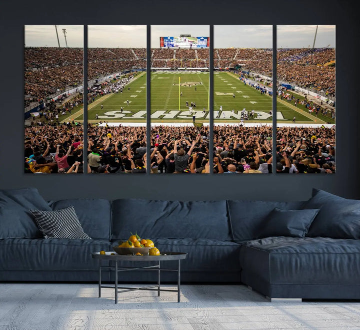 The living room features premium artwork, the "UCF Knights Football Team Print - Orlando FBC Mortgage Stadium Wall Art Canvas Print," a three-panel canvas piece depicting a bustling football stadium. Handmade in the USA, this artwork adds a dynamic and vibrant touch to your space.