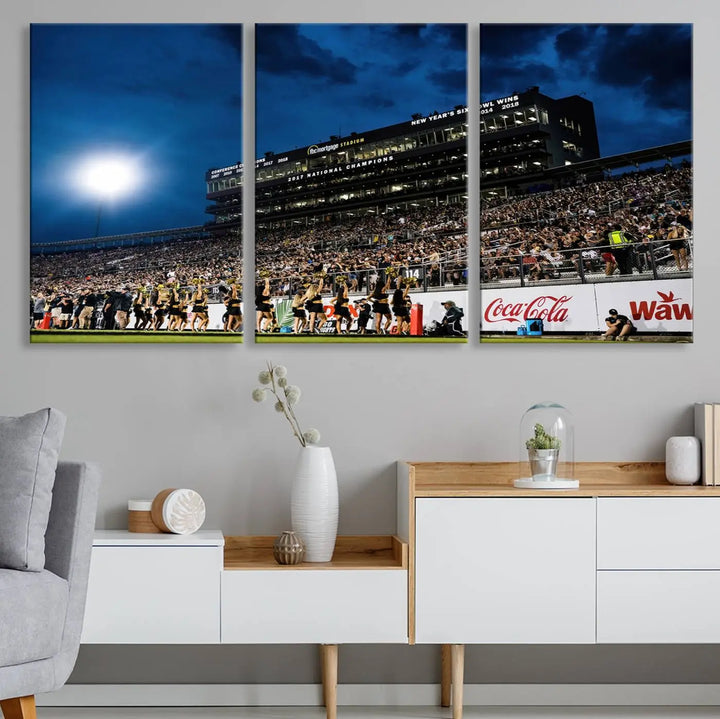 A stunning UCF Knights Football Team print is displayed, capturing the excitement of a night game at the Orlando FBC Mortgage Stadium in front of a lively crowd. This premium canvas offers a gallery-quality finish that brings the scene to life.