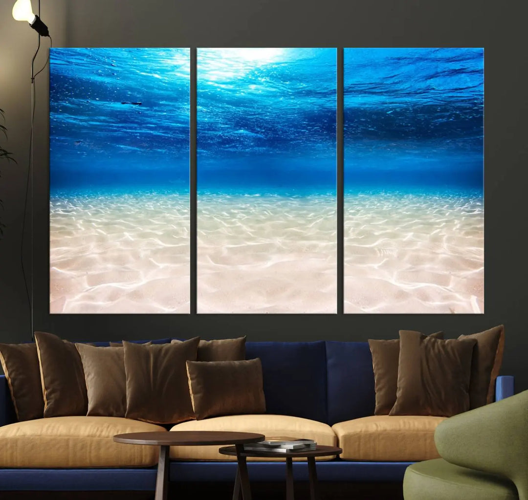 The "Underwater Ocean Scene Giclee Canvas Print – Serene Deep Blue Seascape Wall Art for Coastal Home Decor, Tranquil Sea Bottom Landscape" is gracefully mounted on a wooden wall, creating the perfect marine-themed home decor with its depiction of sunlight illuminating the sandy ocean floor.