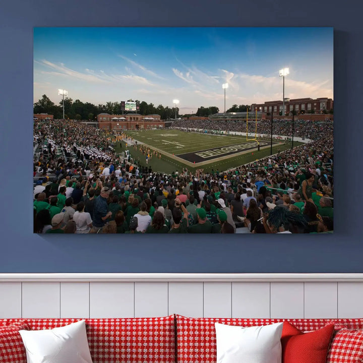 Above the dining table hangs a premium canvas triptych depicting Charlotte Jerry Richardson Stadium, home of the University of Charlotte 49ers Football Team. The scene is alive with a nighttime atmosphere, bustling with a large crowd under bright stadium lights. This stunning art piece is expertly handmade in the USA and adds vibrant energy to your living space.