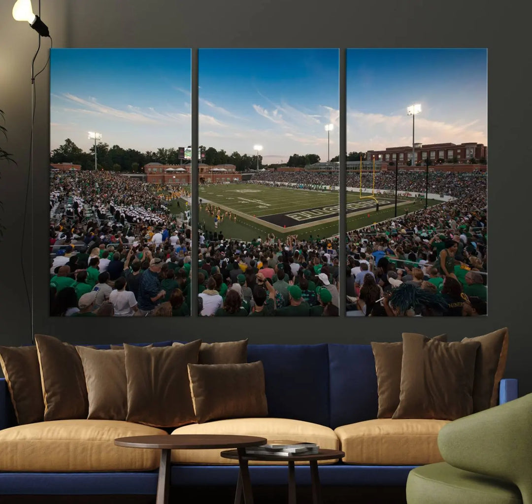 Above the dining table hangs a premium canvas triptych depicting Charlotte Jerry Richardson Stadium, home of the University of Charlotte 49ers Football Team. The scene is alive with a nighttime atmosphere, bustling with a large crowd under bright stadium lights. This stunning art piece is expertly handmade in the USA and adds vibrant energy to your living space.