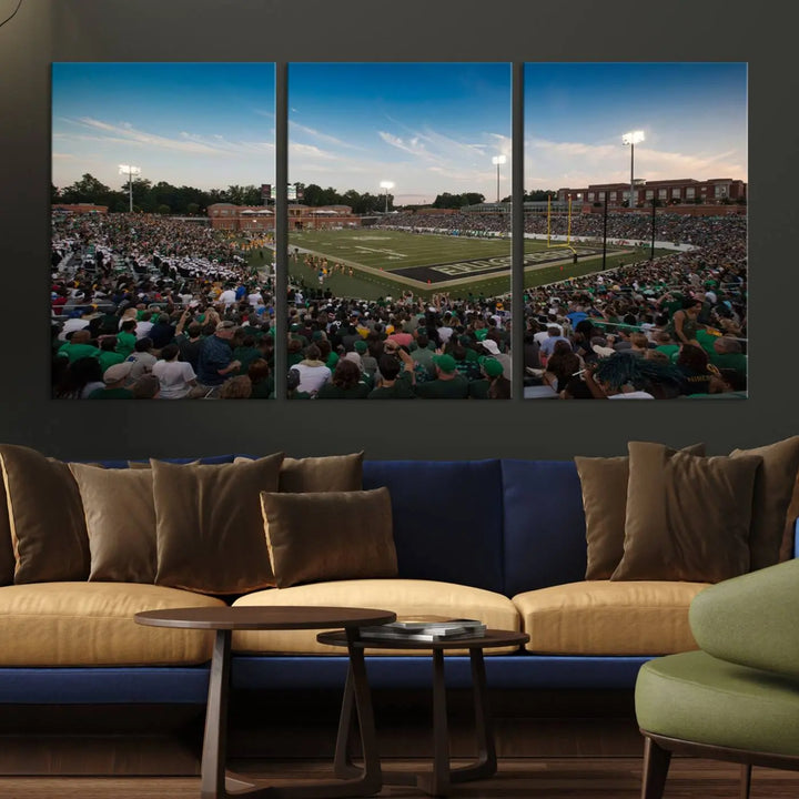 Above the dining table hangs a premium canvas triptych depicting Charlotte Jerry Richardson Stadium, home of the University of Charlotte 49ers Football Team. The scene is alive with a nighttime atmosphere, bustling with a large crowd under bright stadium lights. This stunning art piece is expertly handmade in the USA and adds vibrant energy to your living space.