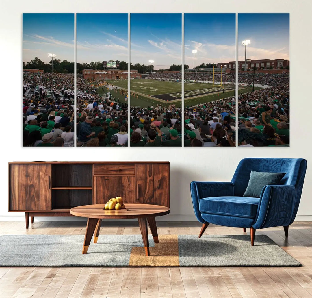 Above the dining table hangs a premium canvas triptych depicting Charlotte Jerry Richardson Stadium, home of the University of Charlotte 49ers Football Team. The scene is alive with a nighttime atmosphere, bustling with a large crowd under bright stadium lights. This stunning art piece is expertly handmade in the USA and adds vibrant energy to your living space.