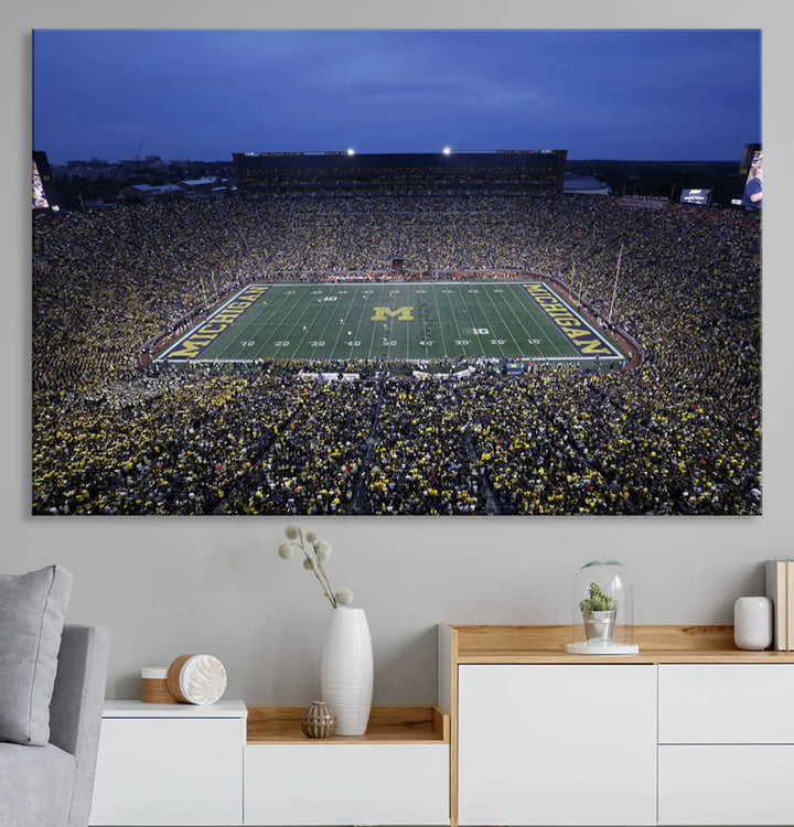 Experience the excitement and grandeur of a packed football stadium at night with this University of Michigan Wolverines Football Team Print. Featuring a panoramic view of the iconic Ann Arbor Michigan Stadium and its green field adorned with a large M logo, this canvas artwork offers a gallery-quality finish that brings an energetic moment into your space.