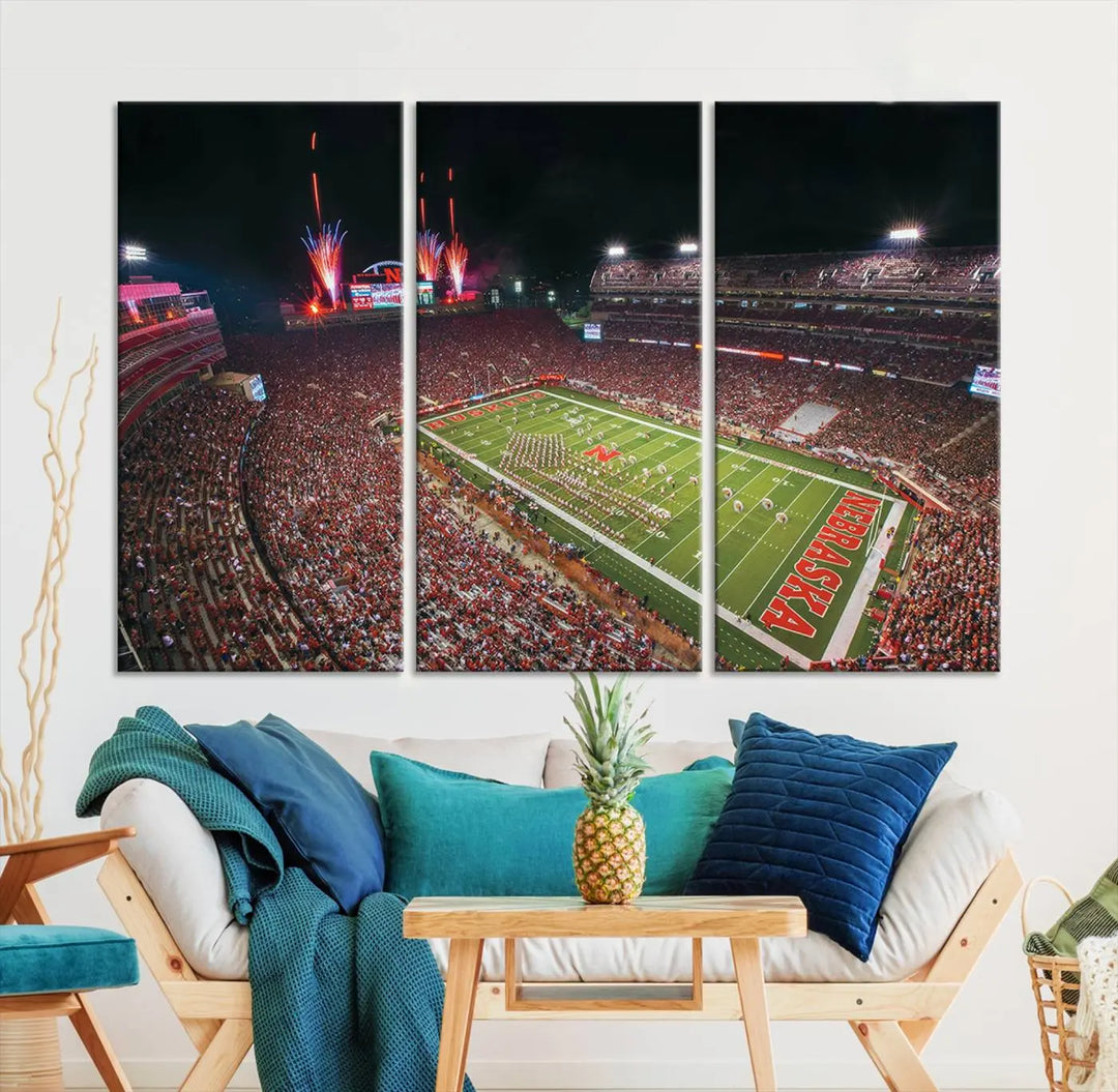 The University of Nebraska Cornhuskers Football Team Print, featuring Lincoln Memorial Stadium in a vibrant triptych canvas with fireworks above and a gallery-quality finish, is elegantly displayed.