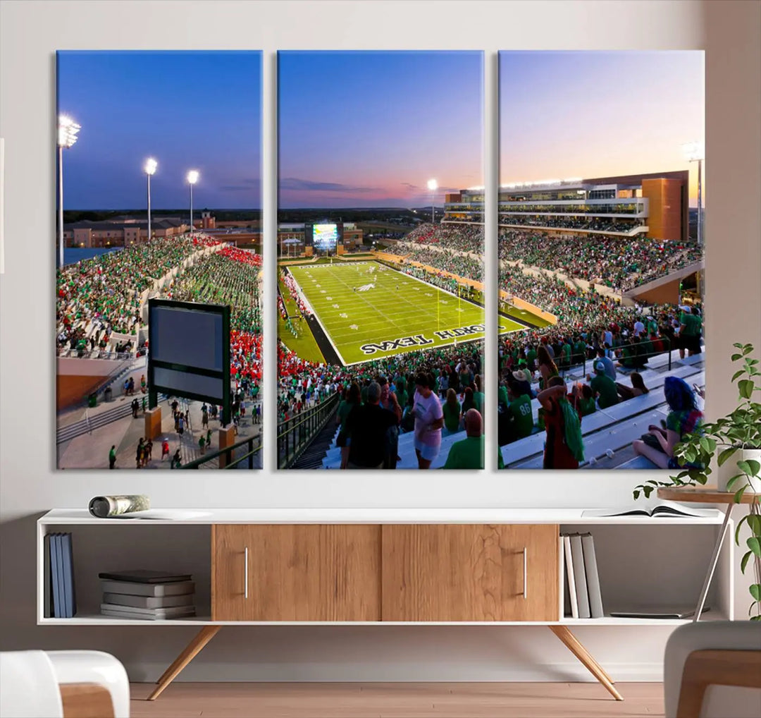 A panoramic triptych of the University of North Texas Mean Green Football Team in a packed Denton DATCU Stadium under evening lights, mounted as premium canvas wall art.