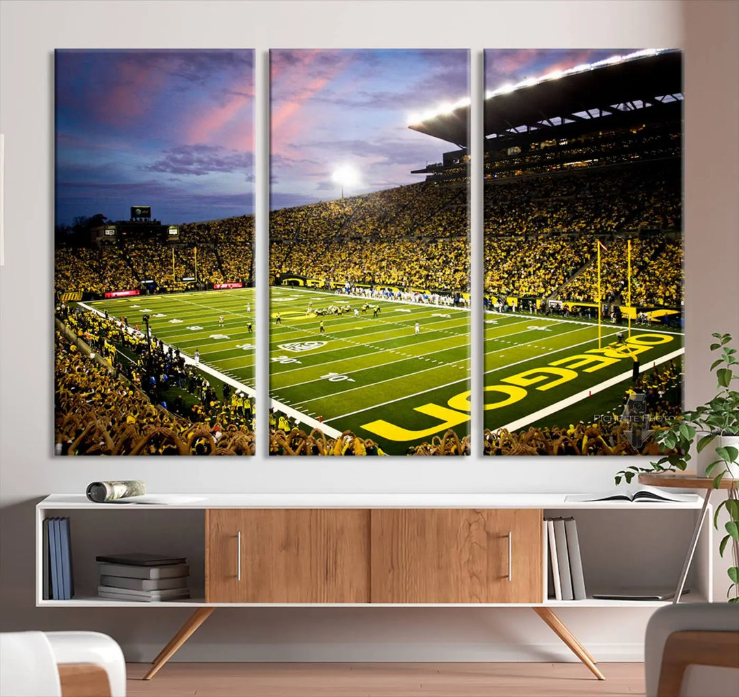 The living room showcases a triptych titled "University of Oregon Ducks Football Team Print - Eugene Autzen Stadium Wall Art Canvas Print," exhibiting a football stadium at sunset with a premium gallery-quality finish.