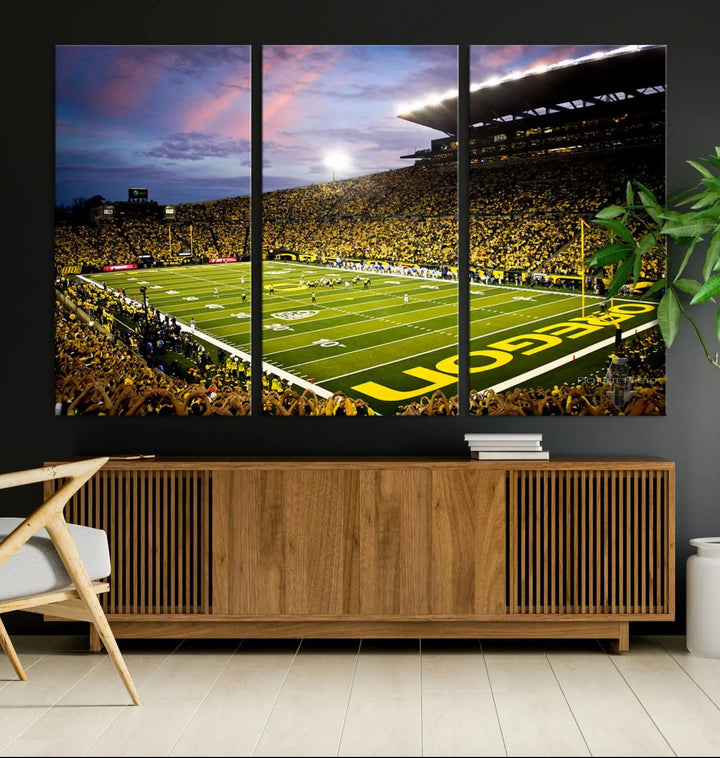 The living room showcases a triptych titled "University of Oregon Ducks Football Team Print - Eugene Autzen Stadium Wall Art Canvas Print," exhibiting a football stadium at sunset with a premium gallery-quality finish.