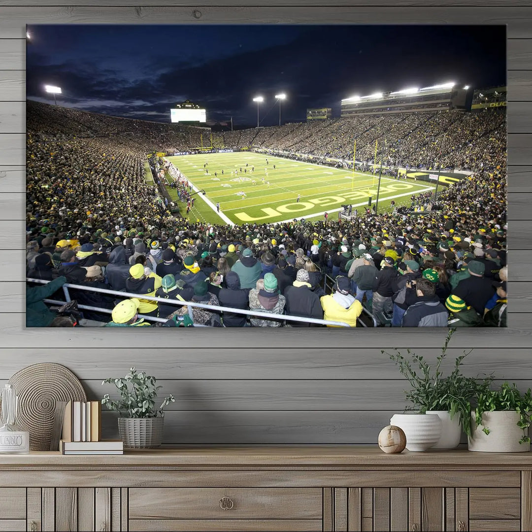 The living room features a triptych of wall art titled "University of Oregon Ducks Football Team Print - Eugene Autzen Stadium Wall Art Canvas Print," which depicts a bustling football stadium at night. Crafted on premium canvas and handmade in the USA, it serves as a striking focal point in the space.