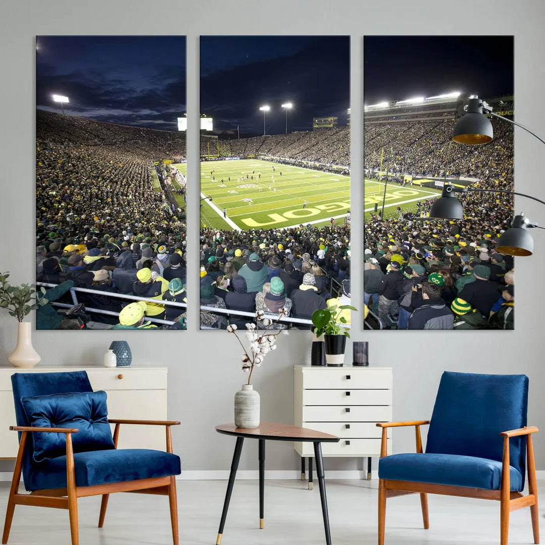 The living room features a triptych of wall art titled "University of Oregon Ducks Football Team Print - Eugene Autzen Stadium Wall Art Canvas Print," which depicts a bustling football stadium at night. Crafted on premium canvas and handmade in the USA, it serves as a striking focal point in the space.