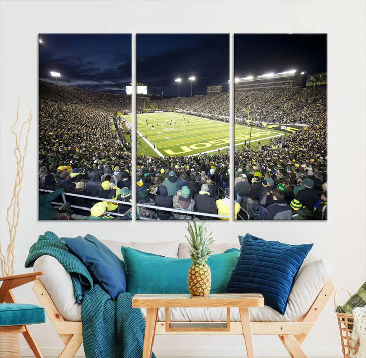 The living room features a triptych of wall art titled "University of Oregon Ducks Football Team Print - Eugene Autzen Stadium Wall Art Canvas Print," which depicts a bustling football stadium at night. Crafted on premium canvas and handmade in the USA, it serves as a striking focal point in the space.