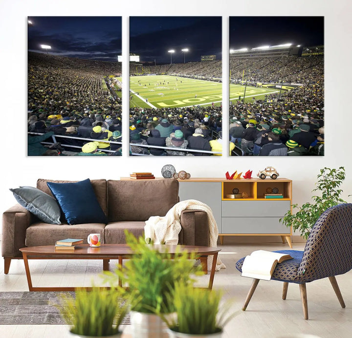 The living room features a triptych of wall art titled "University of Oregon Ducks Football Team Print - Eugene Autzen Stadium Wall Art Canvas Print," which depicts a bustling football stadium at night. Crafted on premium canvas and handmade in the USA, it serves as a striking focal point in the space.