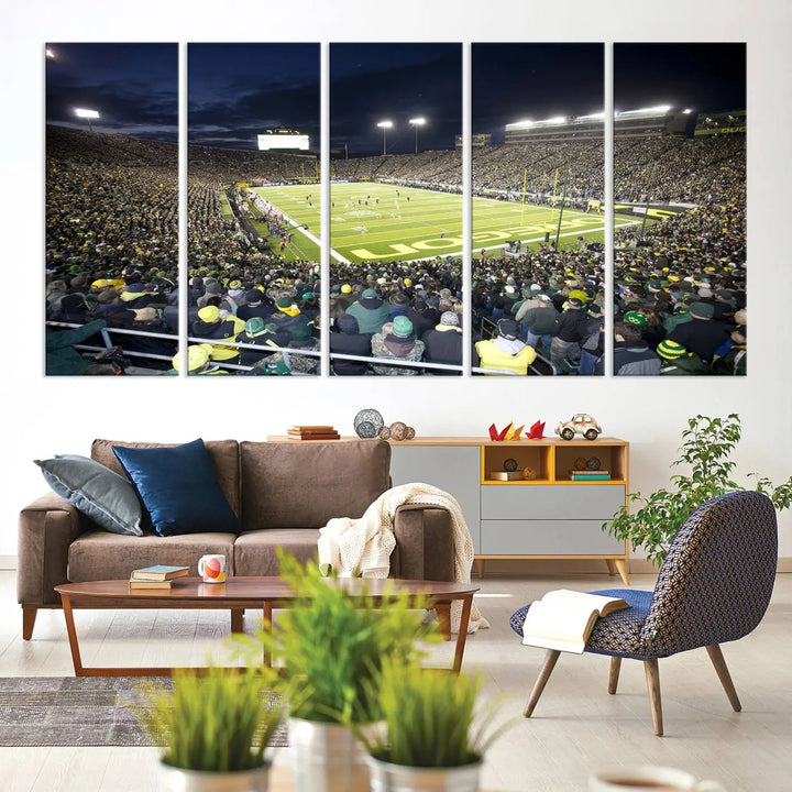 The living room features a triptych of wall art titled "University of Oregon Ducks Football Team Print - Eugene Autzen Stadium Wall Art Canvas Print," which depicts a bustling football stadium at night. Crafted on premium canvas and handmade in the USA, it serves as a striking focal point in the space.