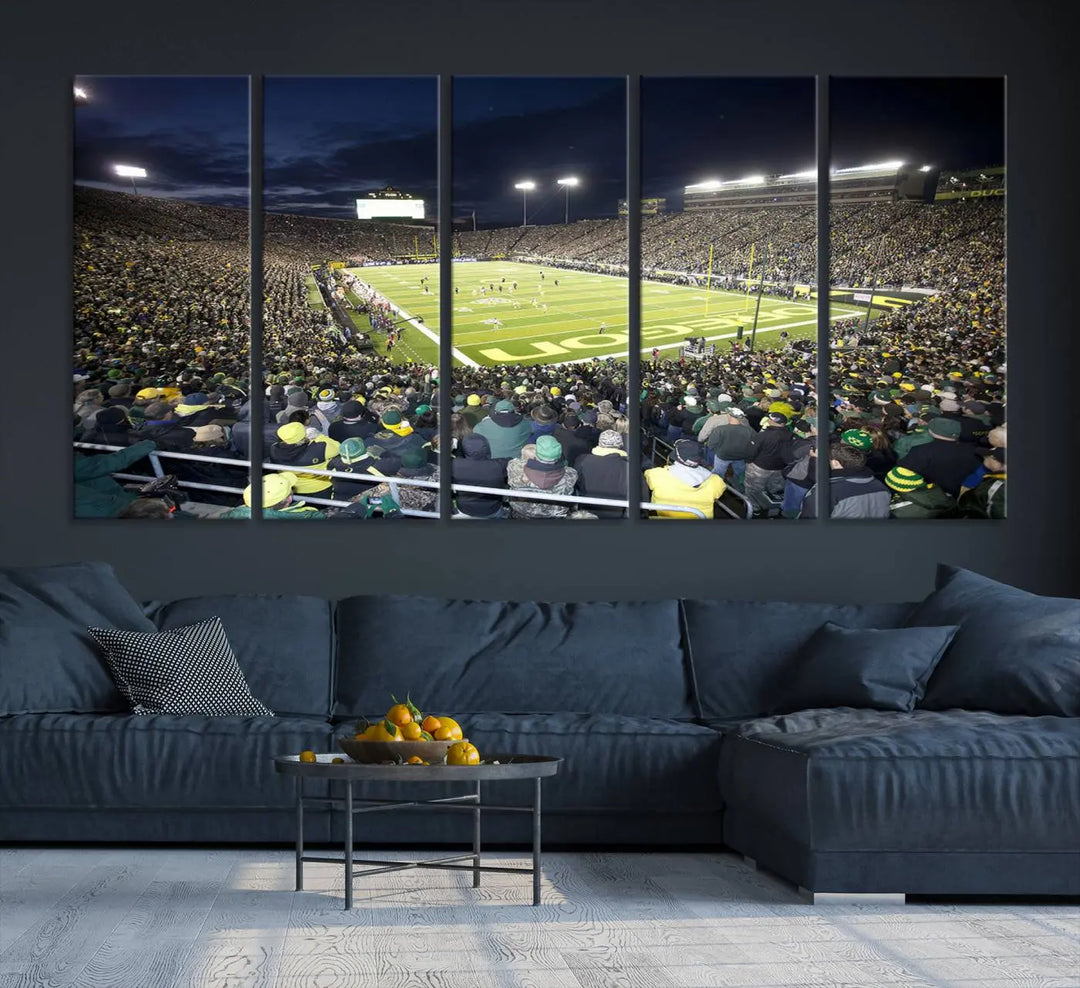 The living room features a triptych of wall art titled "University of Oregon Ducks Football Team Print - Eugene Autzen Stadium Wall Art Canvas Print," which depicts a bustling football stadium at night. Crafted on premium canvas and handmade in the USA, it serves as a striking focal point in the space.