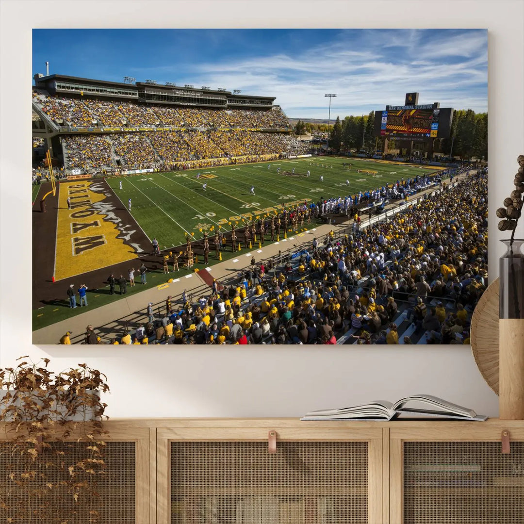 A premium canvas triptych, handmade in the USA, features the University of Wyoming Cowboys Football Team at Laramie Jonah Field as striking wall art on a beige wall.