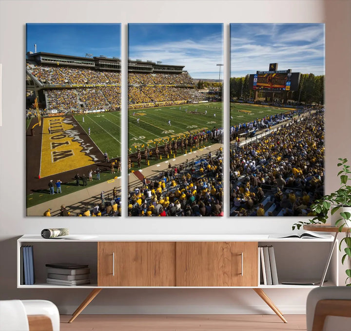 A premium canvas triptych, handmade in the USA, features the University of Wyoming Cowboys Football Team at Laramie Jonah Field as striking wall art on a beige wall.