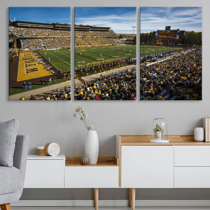 A premium canvas triptych, handmade in the USA, features the University of Wyoming Cowboys Football Team at Laramie Jonah Field as striking wall art on a beige wall.