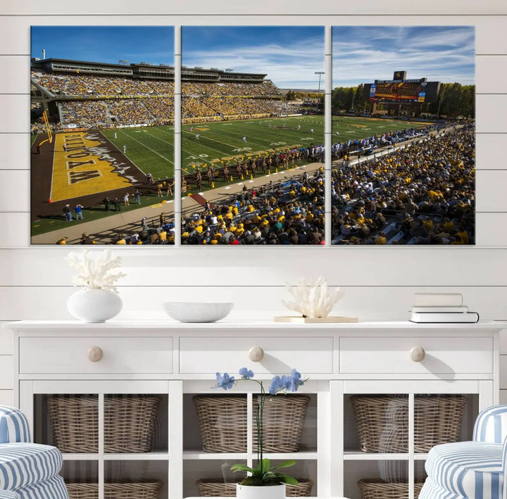 A premium canvas triptych, handmade in the USA, features the University of Wyoming Cowboys Football Team at Laramie Jonah Field as striking wall art on a beige wall.