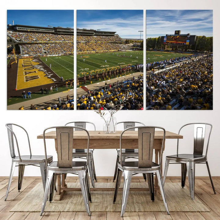 A premium canvas triptych, handmade in the USA, features the University of Wyoming Cowboys Football Team at Laramie Jonah Field as striking wall art on a beige wall.