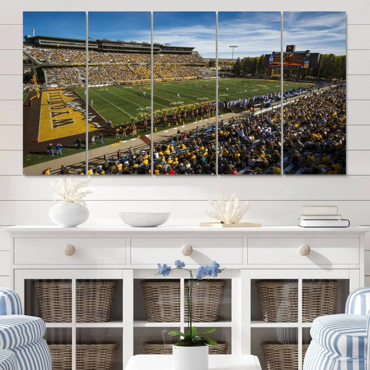 A premium canvas triptych, handmade in the USA, features the University of Wyoming Cowboys Football Team at Laramie Jonah Field as striking wall art on a beige wall.