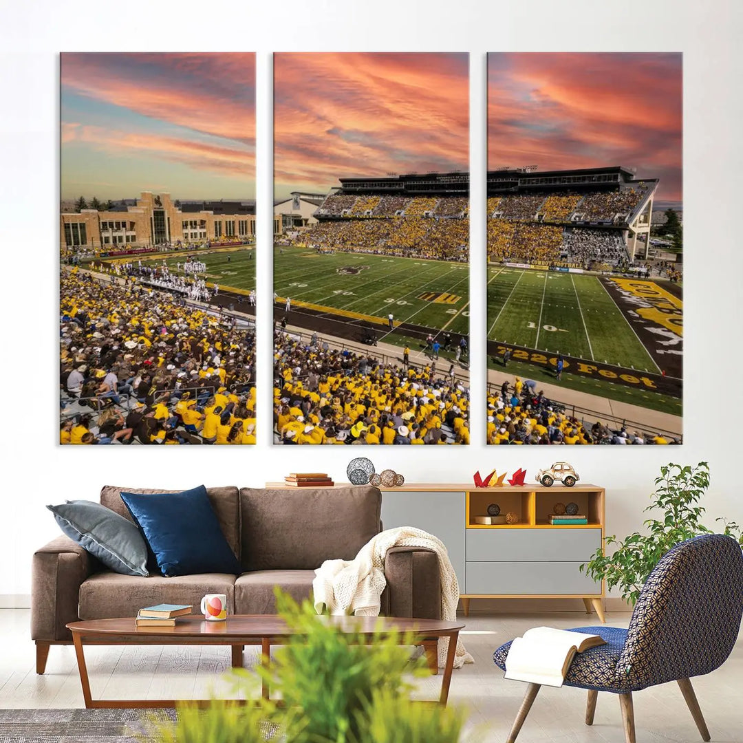 A living room wall showcases a stunning handmade canvas artwork featuring the lively University of Wyoming Cowboys football team at Jonah Field in War Memorial Stadium, beautifully set under a vibrant sunset sky.