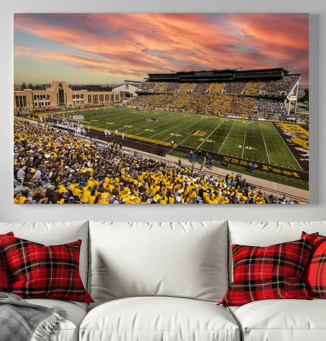 A living room wall showcases a stunning handmade canvas artwork featuring the lively University of Wyoming Cowboys football team at Jonah Field in War Memorial Stadium, beautifully set under a vibrant sunset sky.