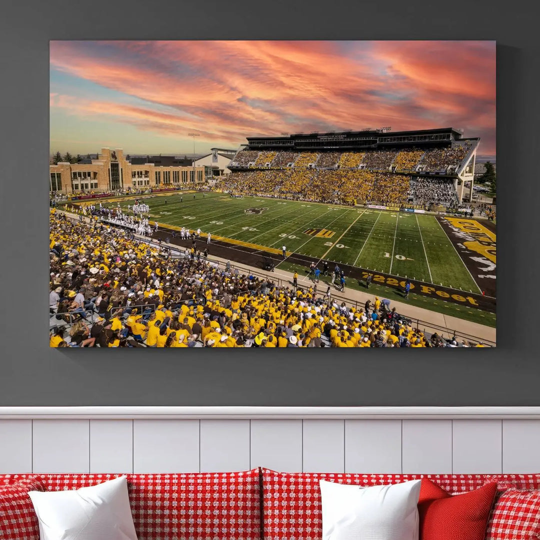 A living room wall showcases a stunning handmade canvas artwork featuring the lively University of Wyoming Cowboys football team at Jonah Field in War Memorial Stadium, beautifully set under a vibrant sunset sky.