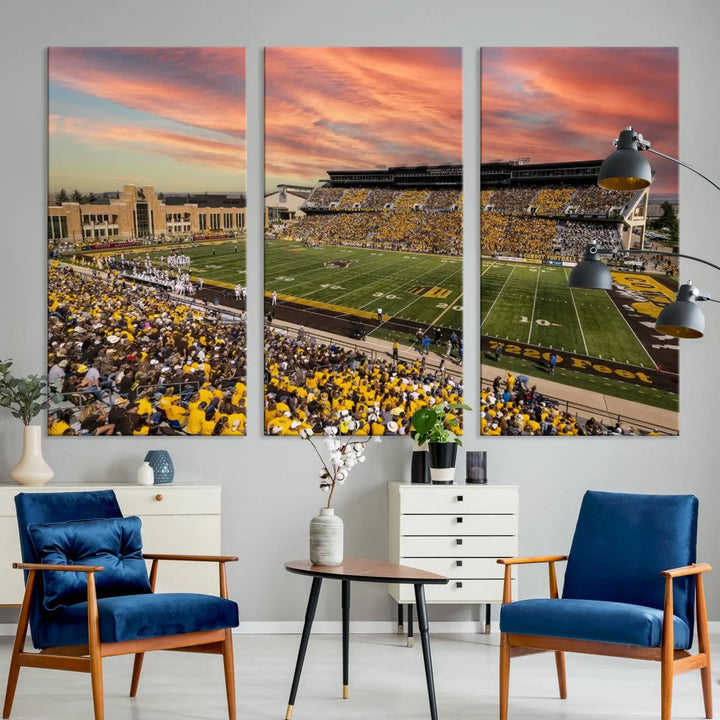 A living room wall showcases a stunning handmade canvas artwork featuring the lively University of Wyoming Cowboys football team at Jonah Field in War Memorial Stadium, beautifully set under a vibrant sunset sky.