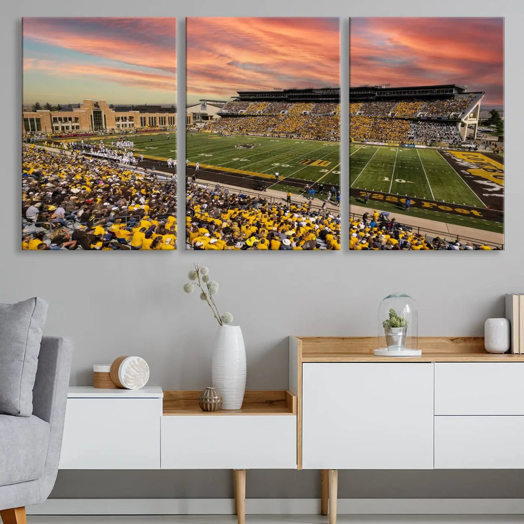 A living room wall showcases a stunning handmade canvas artwork featuring the lively University of Wyoming Cowboys football team at Jonah Field in War Memorial Stadium, beautifully set under a vibrant sunset sky.