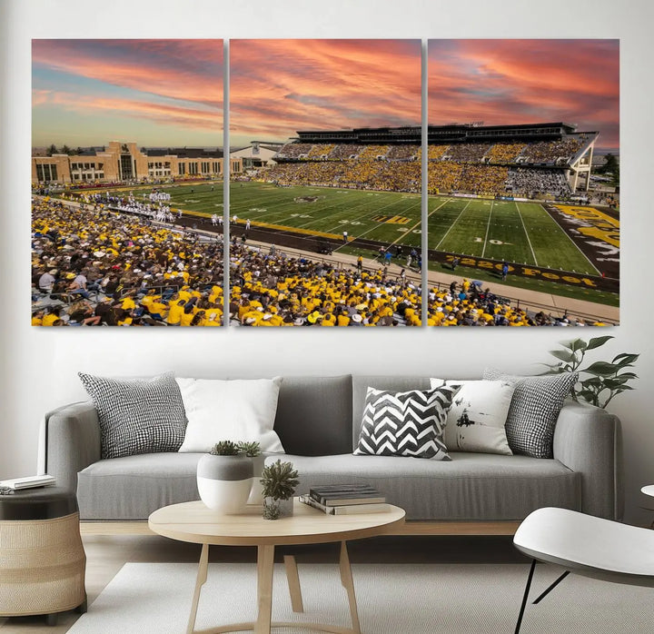 A living room wall showcases a stunning handmade canvas artwork featuring the lively University of Wyoming Cowboys football team at Jonah Field in War Memorial Stadium, beautifully set under a vibrant sunset sky.