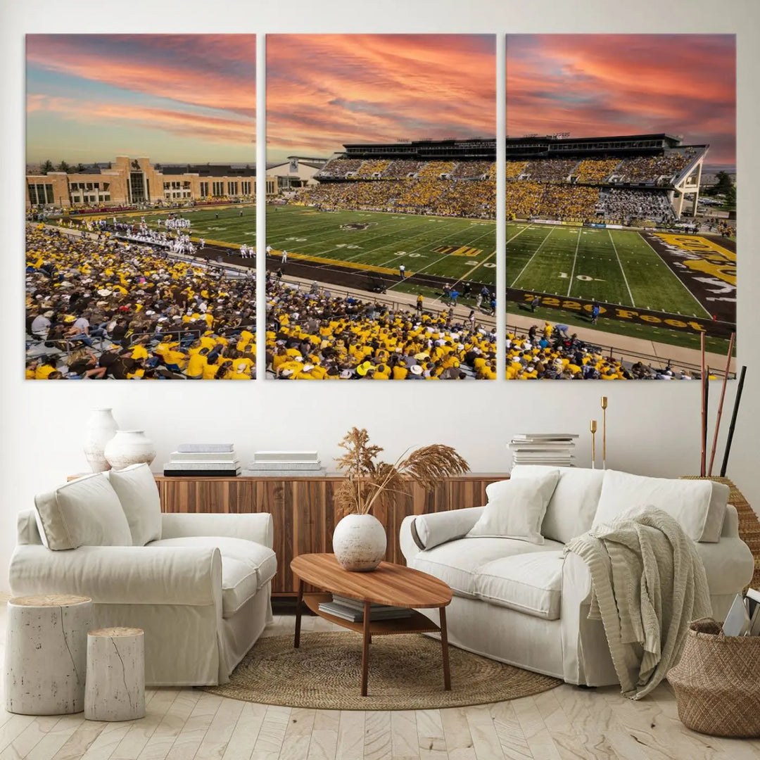 A living room wall showcases a stunning handmade canvas artwork featuring the lively University of Wyoming Cowboys football team at Jonah Field in War Memorial Stadium, beautifully set under a vibrant sunset sky.