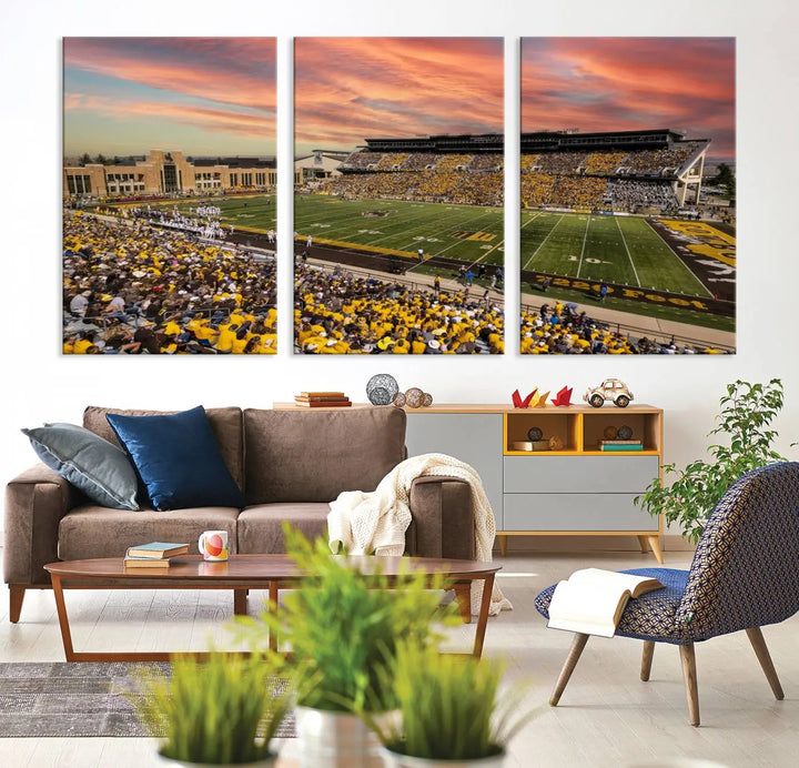 A living room wall showcases a stunning handmade canvas artwork featuring the lively University of Wyoming Cowboys football team at Jonah Field in War Memorial Stadium, beautifully set under a vibrant sunset sky.