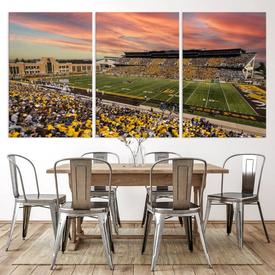 A living room wall showcases a stunning handmade canvas artwork featuring the lively University of Wyoming Cowboys football team at Jonah Field in War Memorial Stadium, beautifully set under a vibrant sunset sky.