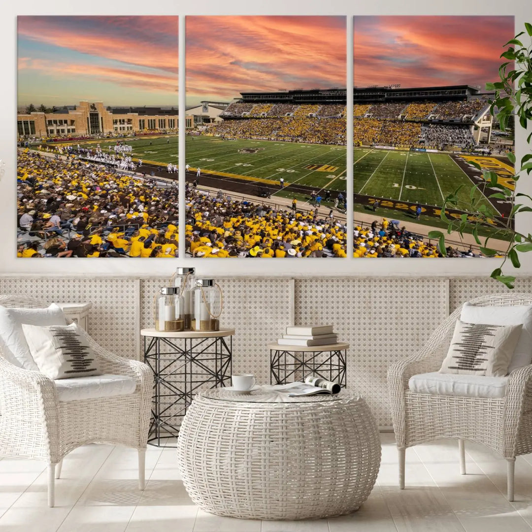 A living room wall showcases a stunning handmade canvas artwork featuring the lively University of Wyoming Cowboys football team at Jonah Field in War Memorial Stadium, beautifully set under a vibrant sunset sky.