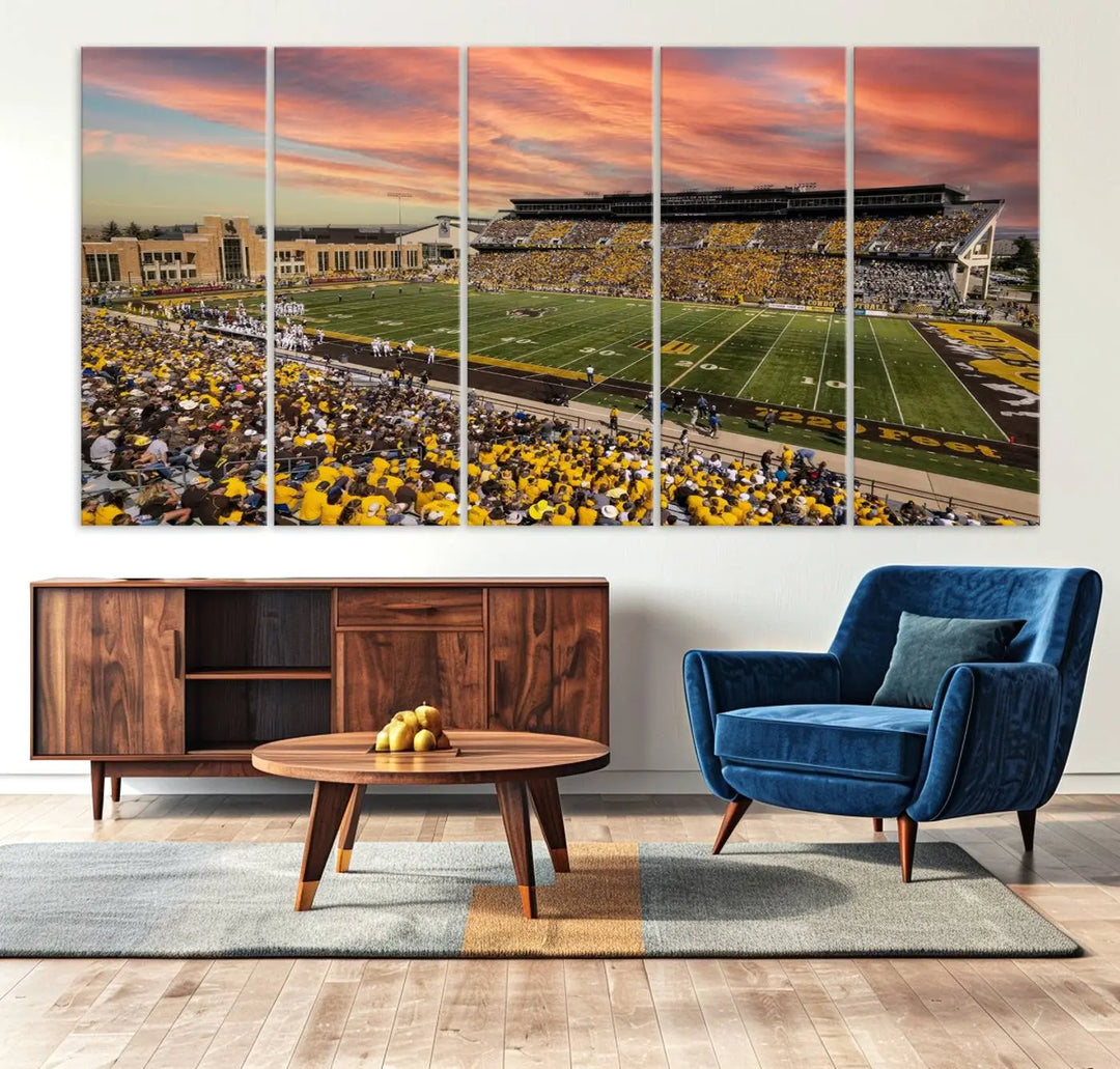 A living room wall showcases a stunning handmade canvas artwork featuring the lively University of Wyoming Cowboys football team at Jonah Field in War Memorial Stadium, beautifully set under a vibrant sunset sky.