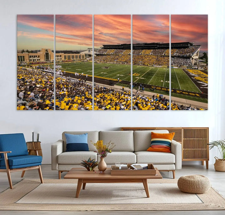 A living room wall showcases a stunning handmade canvas artwork featuring the lively University of Wyoming Cowboys football team at Jonah Field in War Memorial Stadium, beautifully set under a vibrant sunset sky.