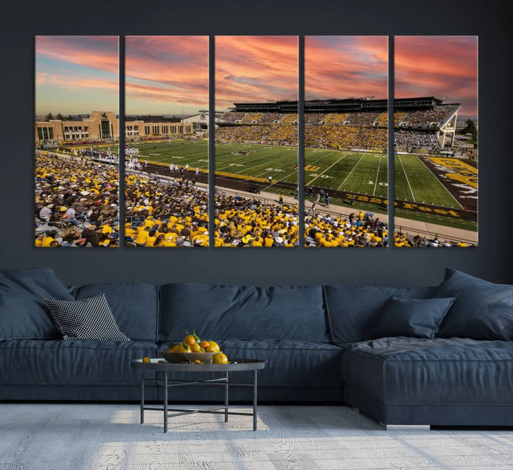 A living room wall showcases a stunning handmade canvas artwork featuring the lively University of Wyoming Cowboys football team at Jonah Field in War Memorial Stadium, beautifully set under a vibrant sunset sky.