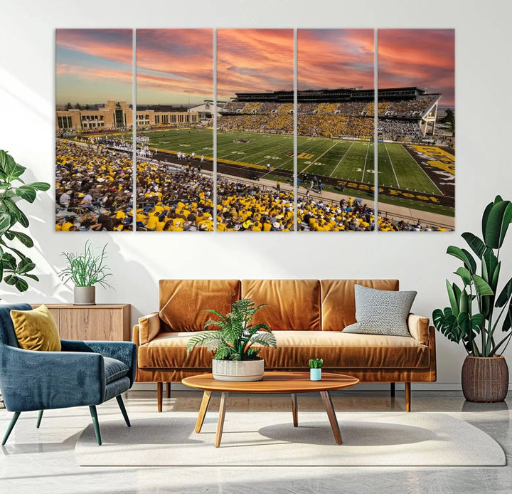 A living room wall showcases a stunning handmade canvas artwork featuring the lively University of Wyoming Cowboys football team at Jonah Field in War Memorial Stadium, beautifully set under a vibrant sunset sky.