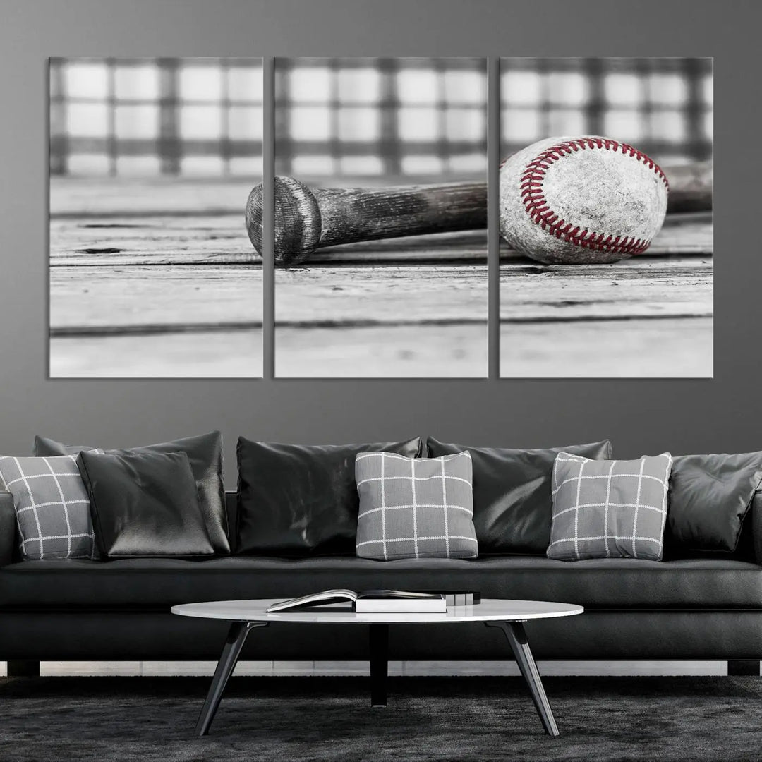 The Vintage Baseball Canvas Wall Art Print showcases a black and white photo of a baseball and bat on a wooden table, divided into three panels. Printed on museum-quality canvas with a UV-protective coating, this artwork arrives ready to hang, bringing timeless charm to any room.