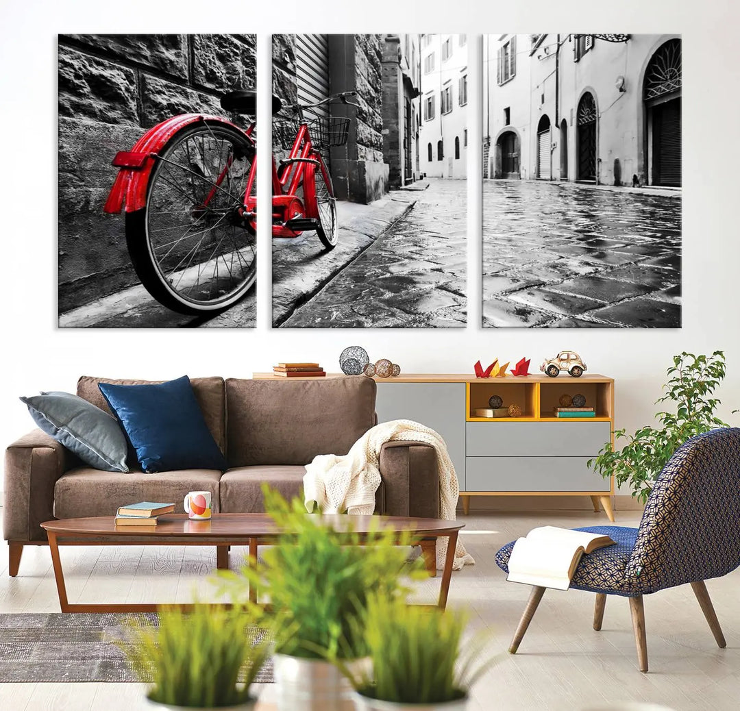 The stunning "Vintage Red Bicycle on the Street Black and White Canvas Wall Art Print" elegantly showcases a red bicycle on a cobblestone street with museum-quality flair.