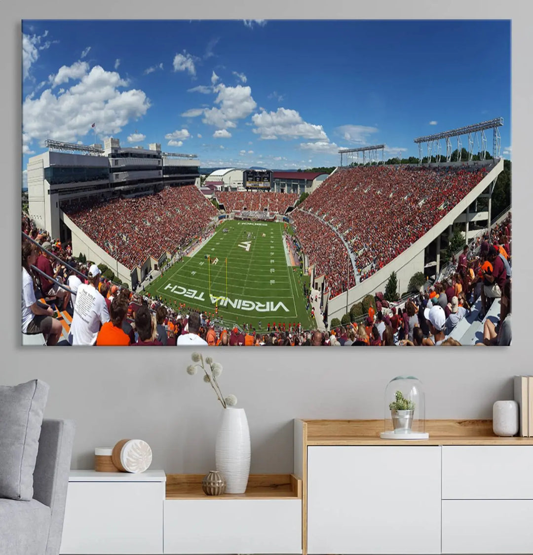 A gallery-quality triptych of the Virginia Tech Hokies Football Team, capturing the vibrant Blacksburg Lane Stadium, hangs in a well-lit, modern room. This handmade canvas artwork from the USA adds a dynamic touch to the space.