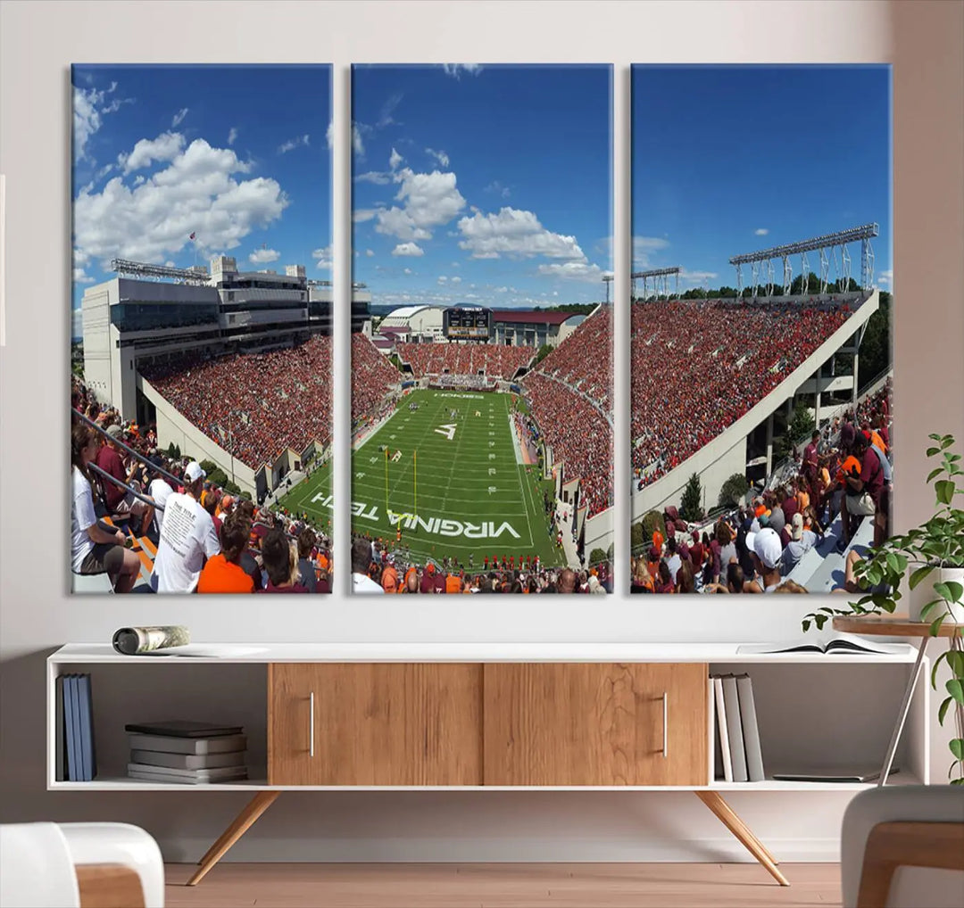 A gallery-quality triptych of the Virginia Tech Hokies Football Team, capturing the vibrant Blacksburg Lane Stadium, hangs in a well-lit, modern room. This handmade canvas artwork from the USA adds a dynamic touch to the space.