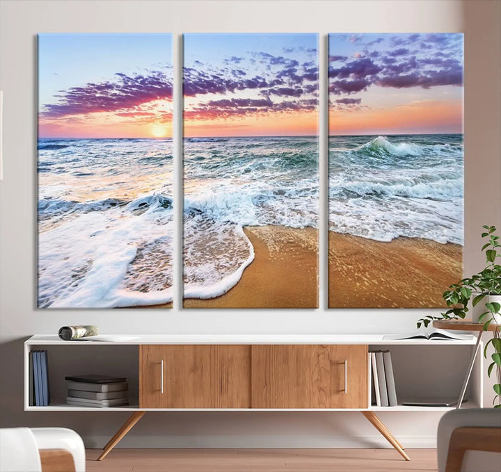 The "Vivid Sunset Ocean Waves Wall Art" hangs on the wall, capturing the serene beauty of the sea. This coastal beach canvas print triptych perfectly enhances living rooms and relaxation spaces.