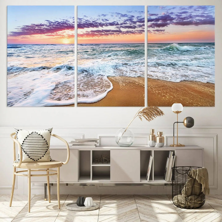 The "Vivid Sunset Ocean Waves Wall Art" hangs on the wall, capturing the serene beauty of the sea. This coastal beach canvas print triptych perfectly enhances living rooms and relaxation spaces.