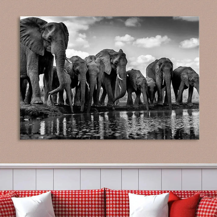 A stunning "Wall Art Animal Canvas Print" featuring a black and white photo of a herd of elephants drinking water is elegantly displayed, gallery wrapped on museum-quality canvas.