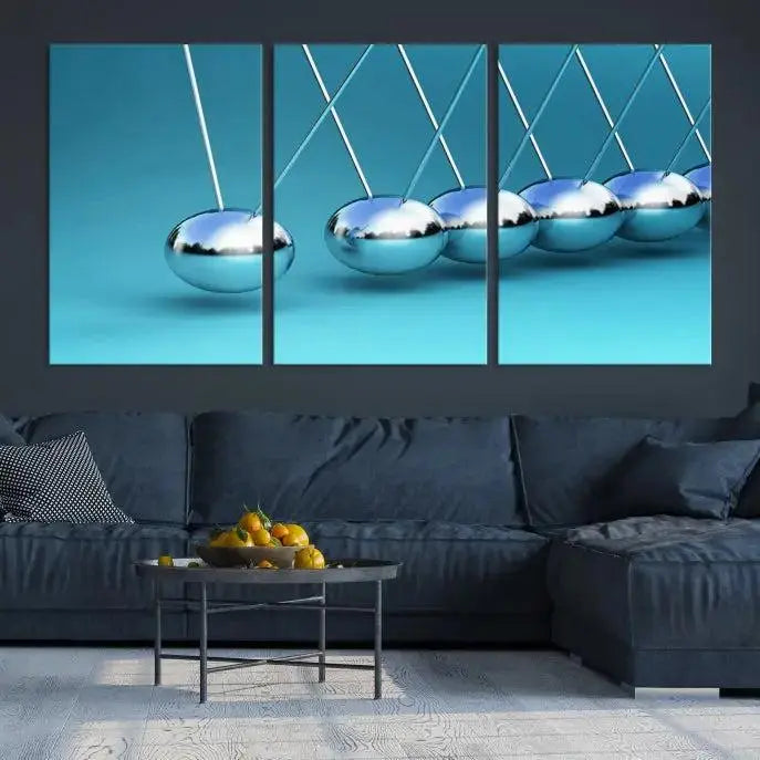 The Wall Art Newton's Cradle Canvas Print is displayed as a triptych on a teal background. Each piece is gallery-wrapped and crafted on museum-quality canvases with a UV-protective coating, ensuring lasting vibrancy and protection.