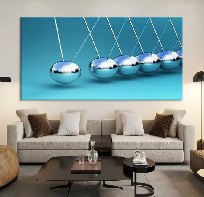 The Wall Art Newton's Cradle Canvas Print is displayed as a triptych on a teal background. Each piece is gallery-wrapped and crafted on museum-quality canvases with a UV-protective coating, ensuring lasting vibrancy and protection.